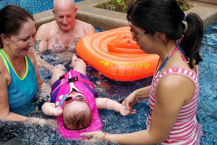 water therapy | AADC News | Rylae-Ann floats on her back in the pool while surrounded by three family members.