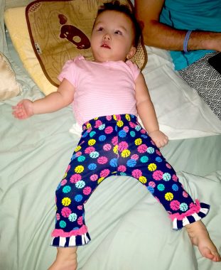 friendships | AADC News | Rylae-Ann reclines on a bed, wearing a pink shirt and polka-dot pants