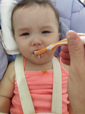 administering medication | AADC News | Rylae-Ann sits in her chair and looks skeptical as she's fed a spoonful of food that contains her medication.
