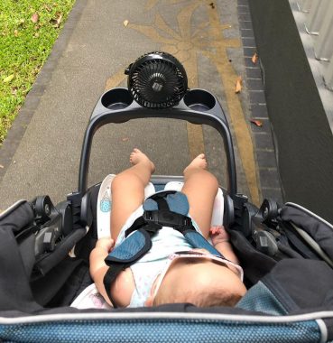 excessive sweating | AADC News | Rylae-Ann sits in her stroller while out for a walk. A portable fan attached to the stroller tray blows air in her direction to keep her cool.