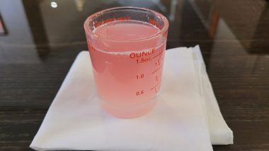 diet and AADC deficiency | AADC News | A glass measuring cup with the pinkish PS128 probiotic