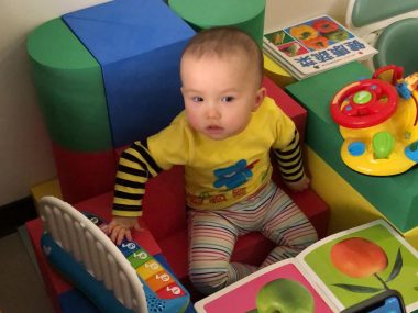 exercises | AADC News | Rylae-Ann sitting, surrounded by toys, with support for her back
