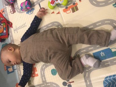exercises | AADC News | an overhead shot of Rylae-Ann, stretched out on the floor with toys nearby