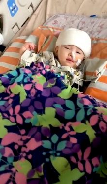 AADC deficiency treatment | AADC News | Richard's daughter Rylae-Ann undergoes gene therapy during a clinical trial. She's wrapped in a colorful blanket in a hospital bed.