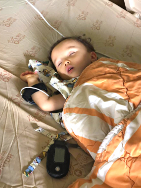 tests to find AADC deficiency | AADC News | Rylae-Ann sleeps while recovering from hospital testing. She is lying under a blanket and is attached to several monitors.
