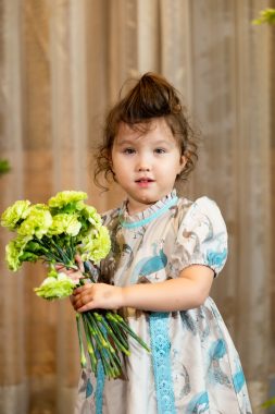 excessive drooling | AADC News | Rylae-Ann poses for a photo wearing a white and blue dress and holding a bouquet of yellow flowers.