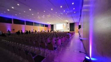 ssiem 2022 | AADC News | A view of a long conference room lit with purple and blue lights. 