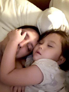 benefits of snuggling | AADC News | aadc deficiency | a photo of Rylae-Ann, in purplish-white clothing, in bed, with her arm around Richard's face.