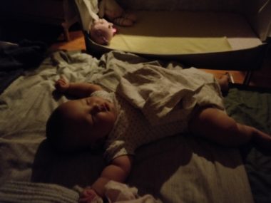 In this photo, an infant rests on what appears to be a mattress. 