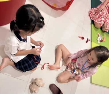 An overhead shot of two young girls sitting on the floor with various toys around them. 