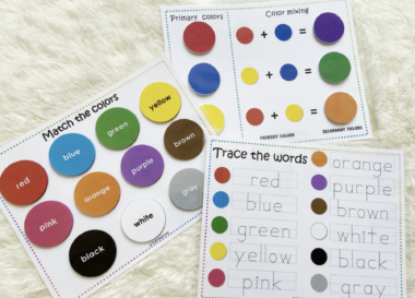 A photo of three pages of an interactive education book for children; one page says "match the colors," another says, "trace the words," and a third is illegible in the photo. Words are printed on colored Velcro circles. 