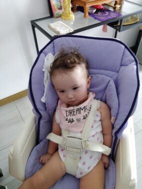 A child reclines in a baby carrier.