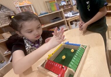 A young child sits at a table playing a board game.