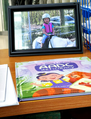 A book rests on a desktop in front of a digital picture frame.
