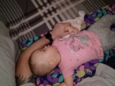 A baby is shown sleeping beside an adult