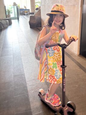 A young girl rides a scooter.