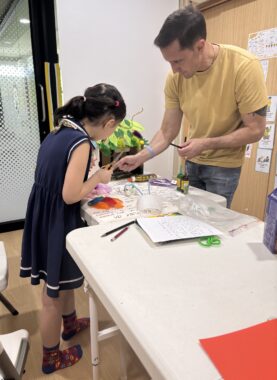 A man and a child work on a project together at a table.
