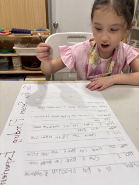 A young girl sits at a desk working on a school assignment.